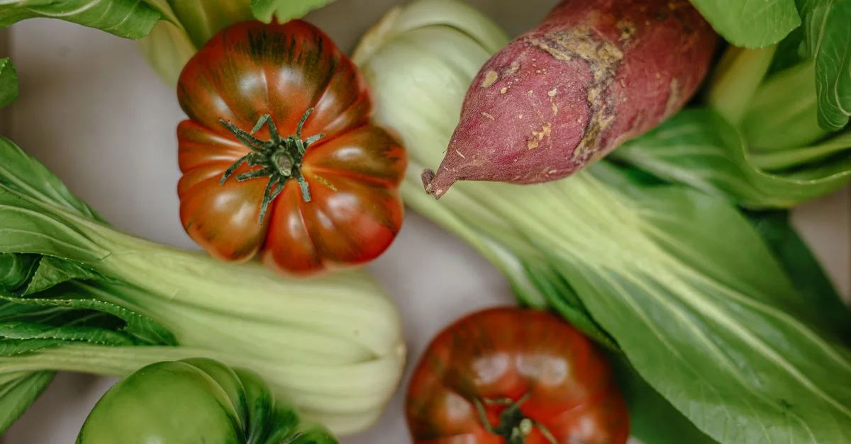 Des légumes frais, y compris des tomates anciennes et des patates douces, en gros plan.